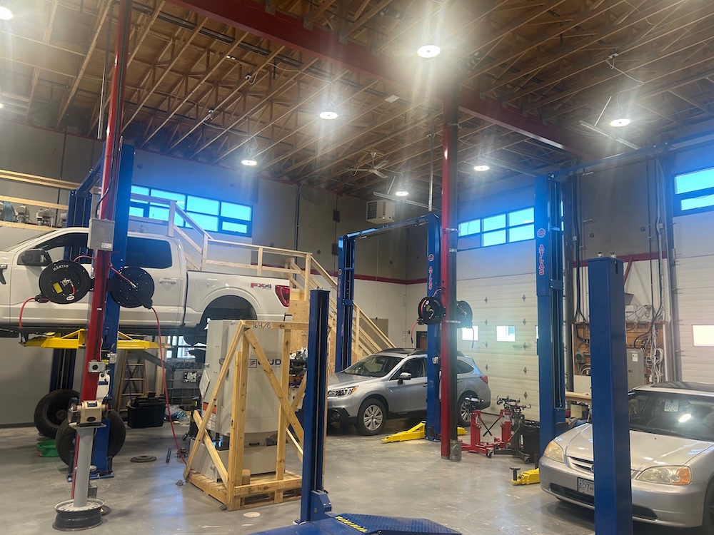Inside the Peninsula Transmission + Automotive shop in Sidney, BC — three vehicles up on the hoists